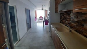 Een moderne keuken met houten kastjes, een grote gootsteen en een betegelde spatwand.