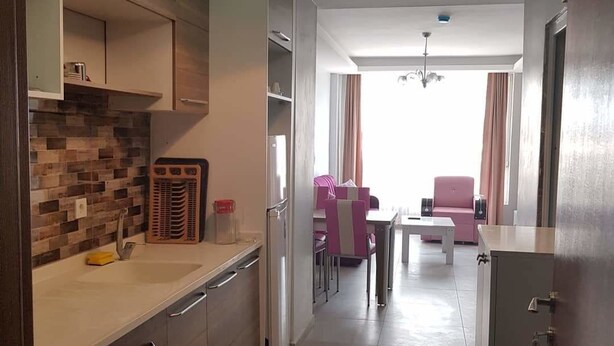 Een moderne keuken met een ingebouwde oven, een eethoek met roze stoelen en uitzicht op de woonkamer.