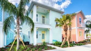 A two-story house with a balcony, surrounded by palm trees and a well-maintained garden. - Sea Breeze Cottage near Disney with Private Hot Tub & Margaritaville Resort &. (Kissimmee)