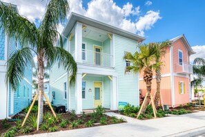 A two-story house with a balcony, surrounded by palm trees and a well-maintained garden.