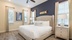 A bedroom with a large bed, two bedside tables, a ceiling fan, and a window with curtains. - Lovely Cottage near Disney | Hot Tub + Resort & Waterpark Access - 8092DR (Kissimmee)