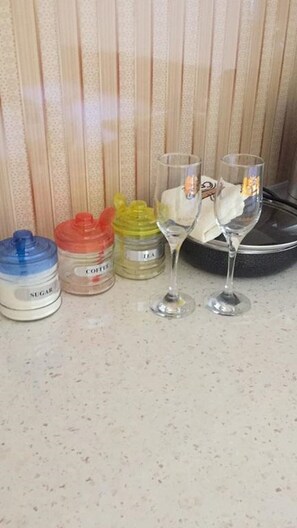 A kitchen counter with three containers labeled sugar, coffee, and tea, and two glasses with tea bags. - 1 Room Delux with a Beautiful View at the Ocean (Batumi)