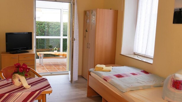 Une chambre à coucher avec un lit, une télévision, une armoire et une vue sur l’extérieur.