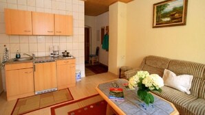 Un espace de vie compact comprenant une cuisine, un canapé et un tableau accroché au mur.