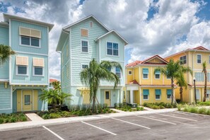 Une rangée de maisons de ville aux couleurs vives, avec un parking devant.