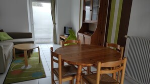 Una sala de estar acogedora con una mesa de comedor de madera, sillas, un sofá y una televisión.