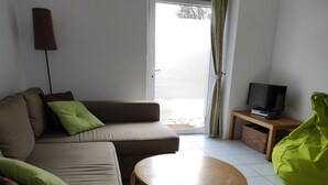 Una sala de estar con sofá, una mesita, televisor y un sillón informal.