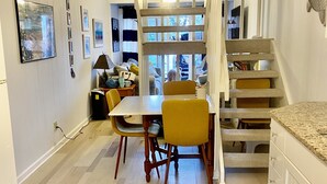 Une cuisine moderne avec un coin repas, un plancher en bois et un escalier menant à l’étage supérieur.