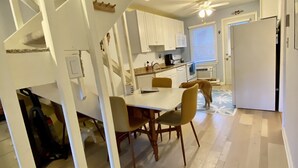 Une cuisine moderne avec des meubles blancs, une table à manger avec des chaises et un escalier menant à l’étage supérieur.