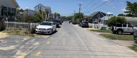 A residential street lined with houses, parked cars, and a clear sky.