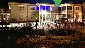 Un bâtiment à deux étages, avec une entrée illuminée de lumière bleue et une voiture garée devant.
