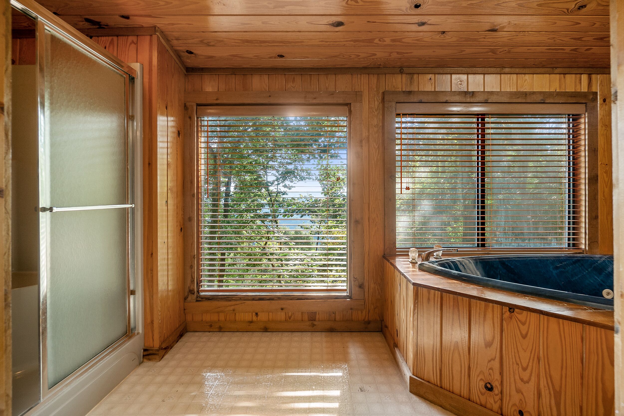 A wooden cabin with a glass door, a window with blinds, and a hot tub.