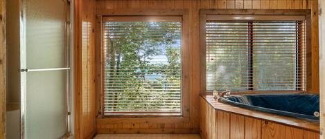 A wooden cabin with a glass door, a window with blinds, and a hot tub.