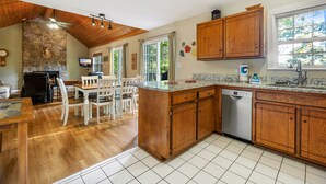 Une cuisine avec des meubles en bois, un lave-vaisselle et un coin repas comprenant des chaises blanches et une table.