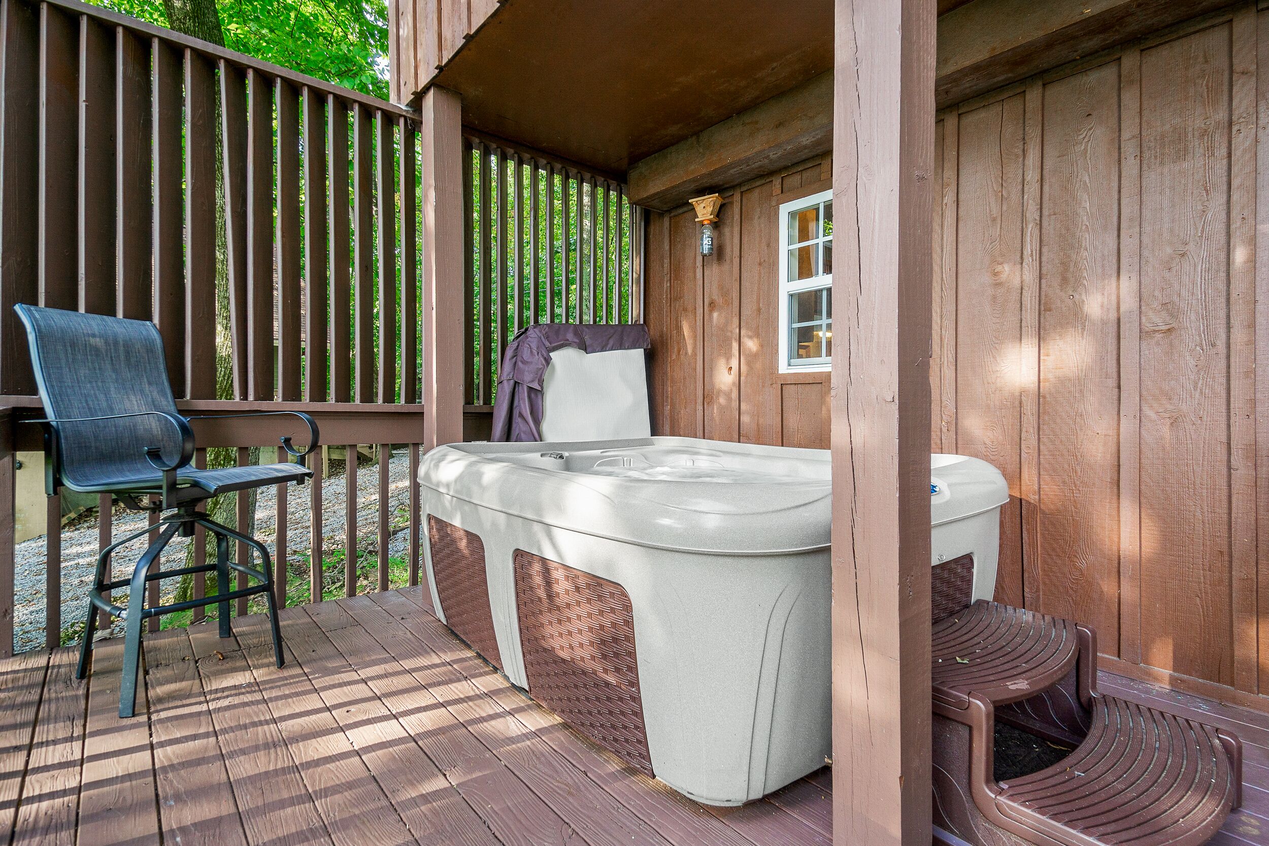 Un jacuzzi con escalones, una silla y una terraza de madera.