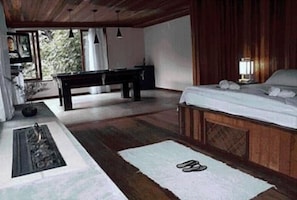 A bedroom with a bed, bedside table, lamp, and a view of the outdoors. - Hotel Warabi (Resende)