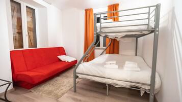 A bunk bed with a red sofa and a window with curtains.