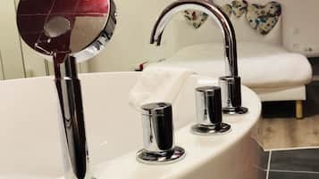 Un baño moderno con una bañera grande, un espejo redondo y un grifo de cromo.