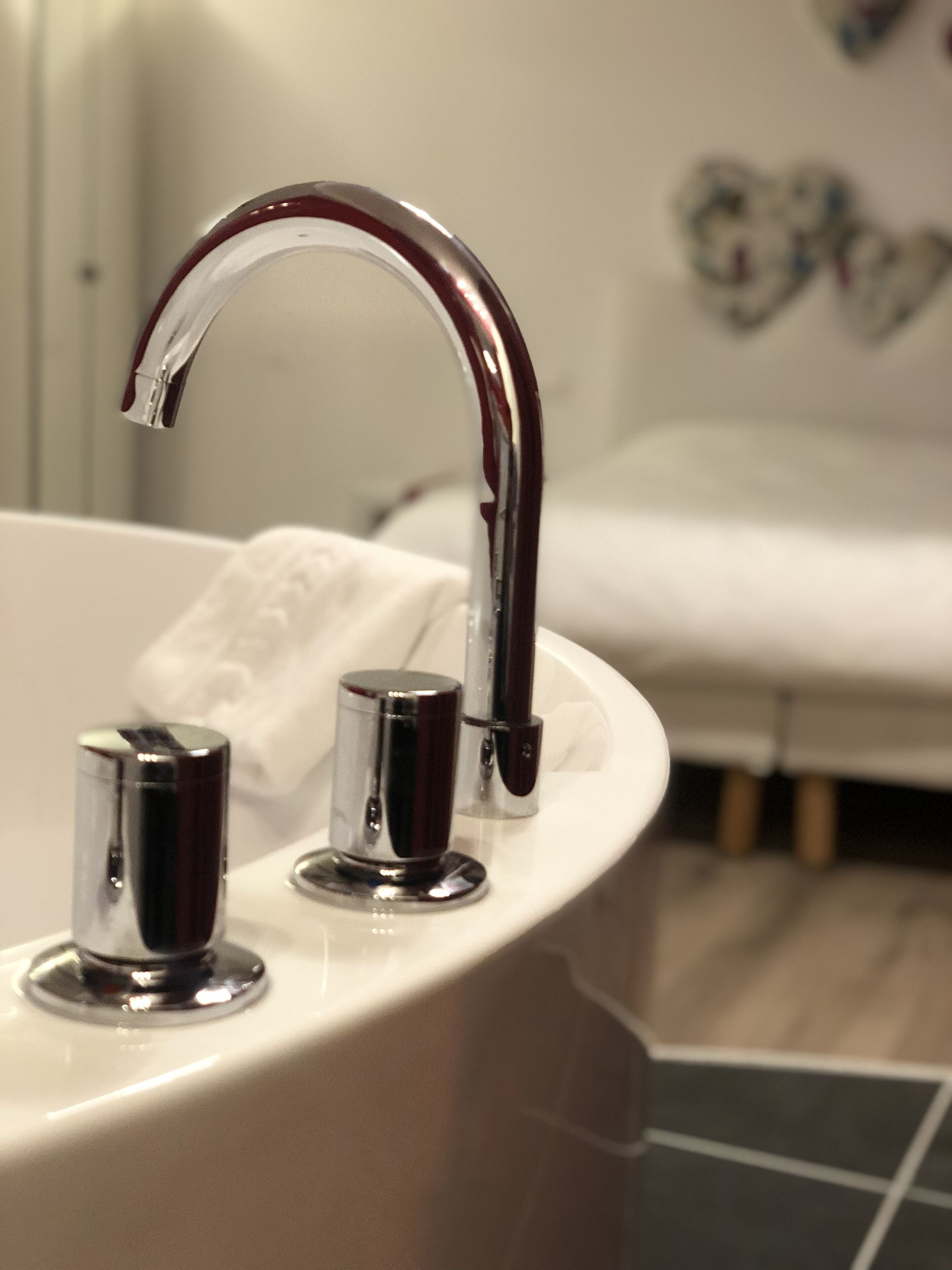 A bathroom with a modern sink, chrome faucet, and a white bathtub.