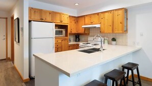 Una cocina moderna con armarios de madera, un refrigerador blanco, un microondas, una estufa y un fregadero.