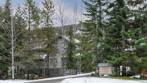 Un edificio rodeado de árboles y nieve, con un letrero.