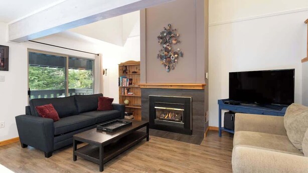 Una sala de estar moderna con chimenea, televisor y estantería.