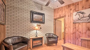 A cozy room with a brick wall, a fireplace, leather chairs, and a wooden door.