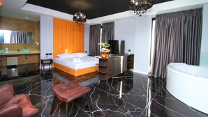 A modern hotel room with a large bed, a sitting area, a TV, and a bathtub. - A&G Hotel (Orikum)