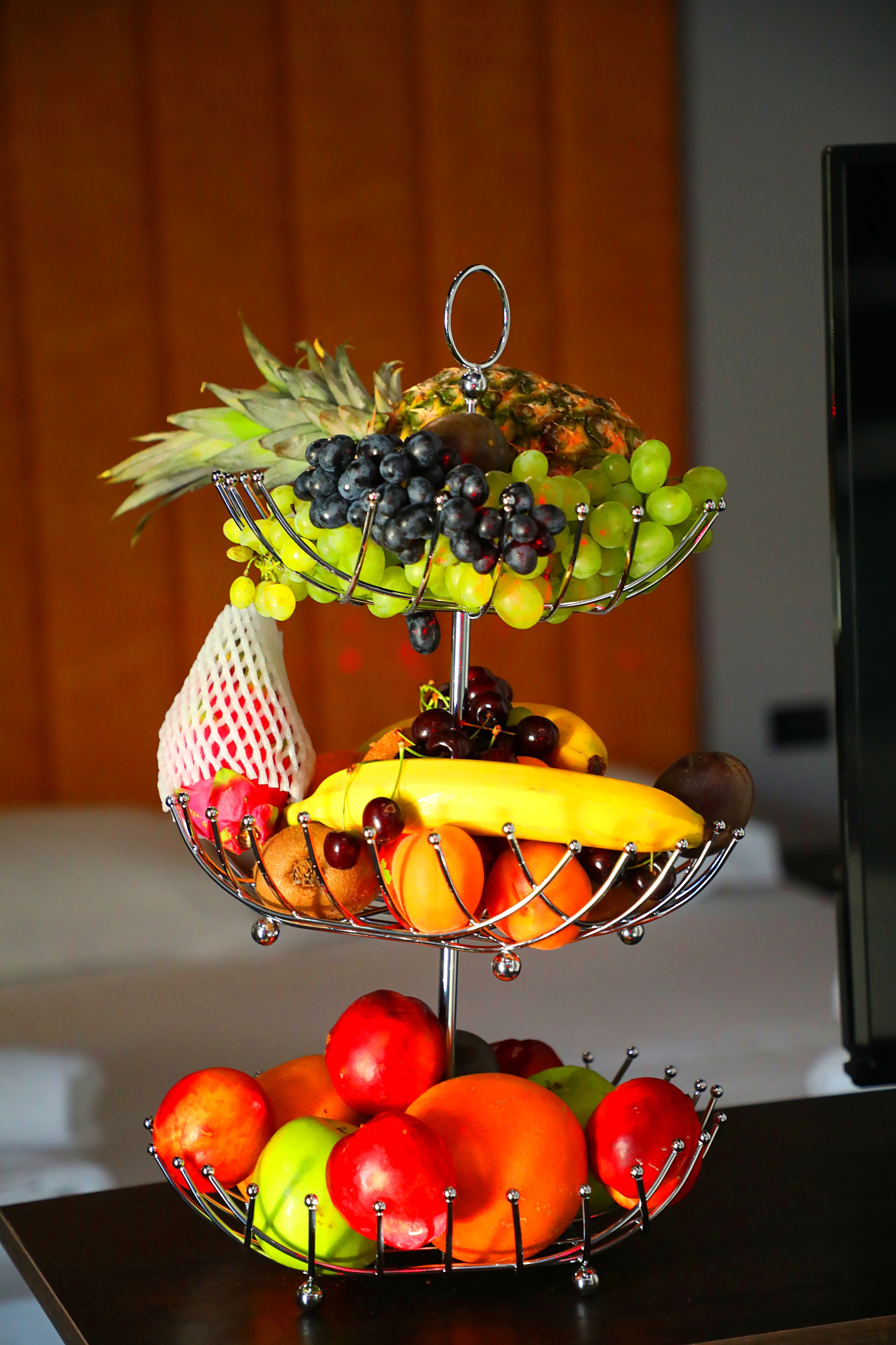 A fruit stand with various fruits and a bag of grapes.