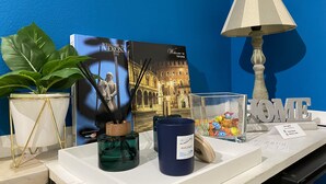Una reception con parete azzurra, un cartello di benvenuto, una pianta in vaso, una statua, una lampada e una selezione di cioccolatini.