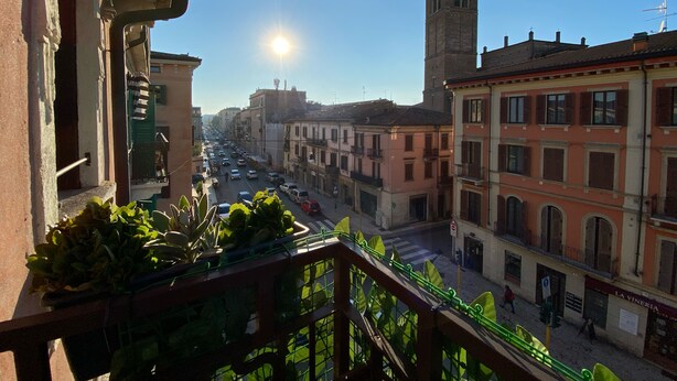 Un balcone con vista su una strada cittadina, edifici e una torre.