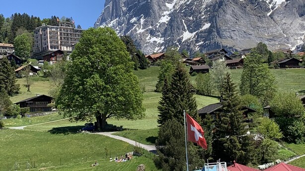 Un hôtel doté d’une piscine, de bâtiments aux toits rouges et surplombant un paysage montagneux.