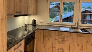 Une cuisine moderne avec des meubles en bois, un plan de travail noir et un lave-vaisselle encastré.