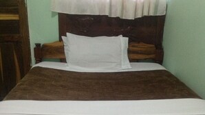A bed with a wooden headboard, a white mattress, and a brown blanket.