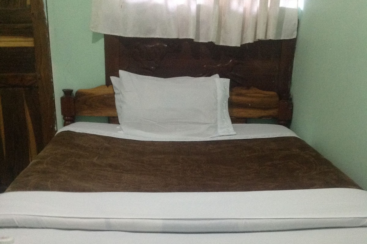 Un lit avec une tête de lit en bois, un matelas blanc et une couverture marron.