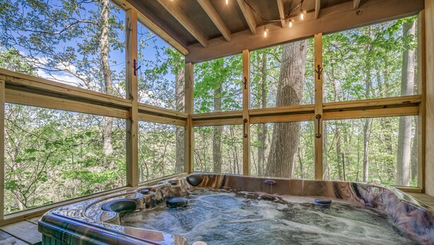 Ein Whirlpool mit Blick auf einen Wald durch große Fenster.