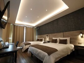 Una habitación de hotel moderna con dos camas, un escritorio y un televisor de pantalla plana.