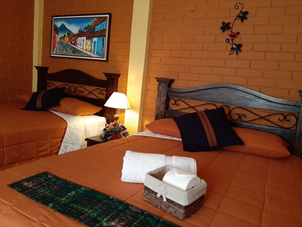 A hotel room with two beds, a painting on the wall, and a decorative wall hanging.