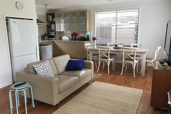 Open plan family, kitchen and dining room with 2 leather couches and Smart TV