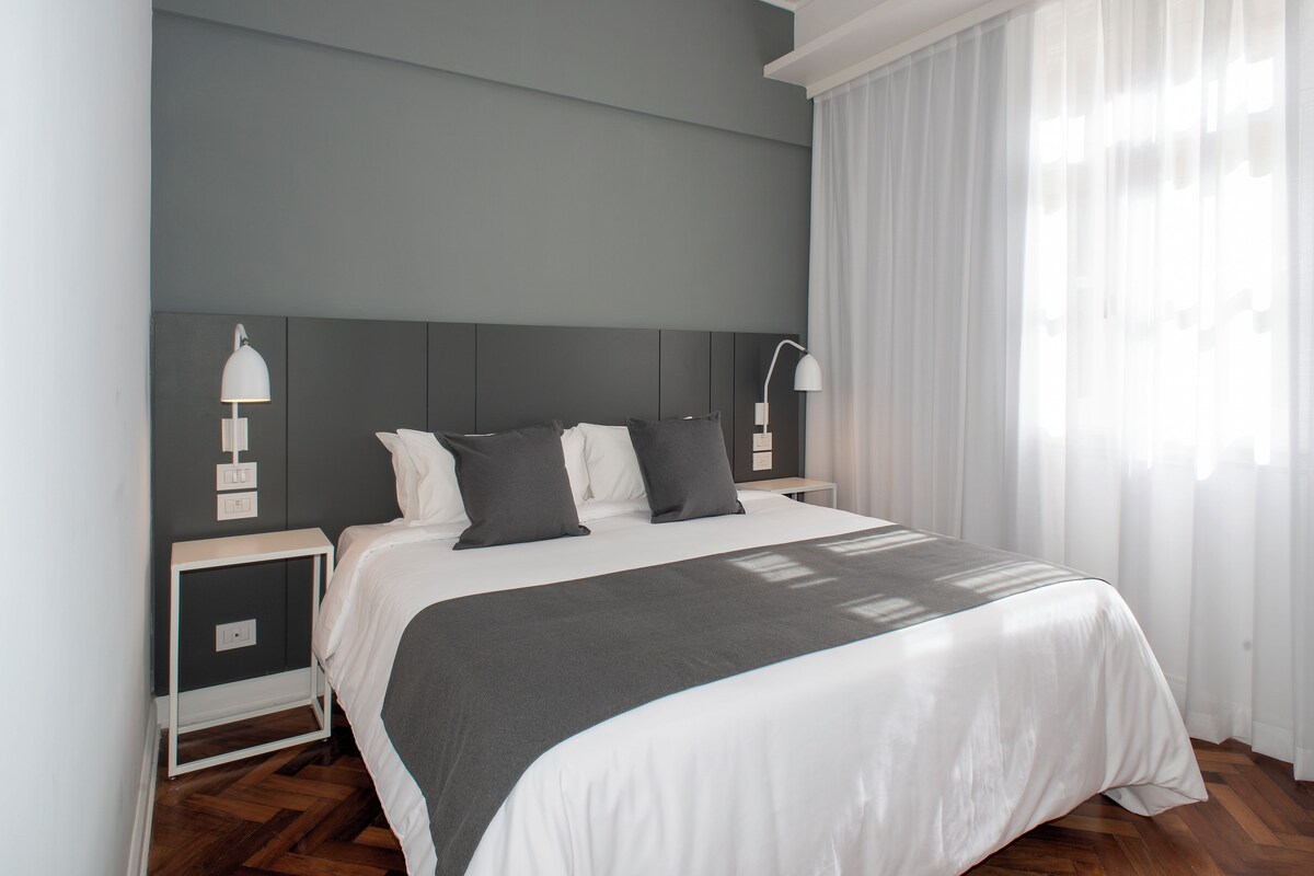 Un dormitorio moderno con una cama grande, dos mesitas de noche y un cabecero.