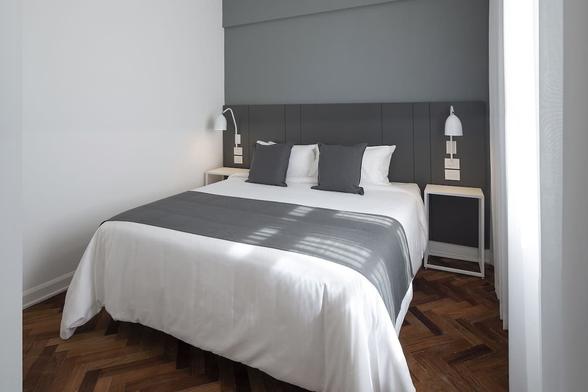 A modern bedroom with a large bed, two bedside tables, and a headboard.