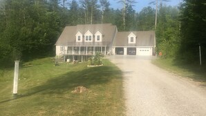 A two-story house with a garage, surrounded by a well-maintained lawn and tall trees.