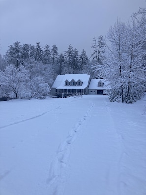 A snow-covered landscape with a house and trees.
