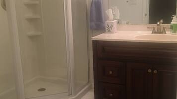 Une salle de bain avec une douche à parois de verre, un meuble-lavabo avec un miroir et un porte-serviettes.