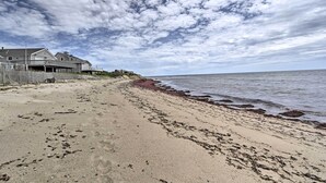 A beach with a wooden fence and a house on the left. - Peaceful Cottage - Steps to Matunuck Beach (South Kingstown)