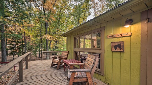 A wooden deck with picnic tables and benches, a green building with a window, and a sign reading "Lucas McCain". - 5 Mi to Raystown Lake Launch: ‘Lucas McCain Cabin’ (Huntingdon)