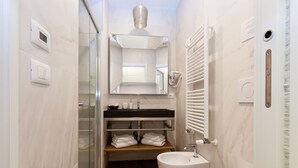 A modern bathroom with a glass shower enclosure, a vanity with a mirror, a sink, and a toilet.