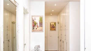 A hallway with white lockers, a small table with a silver elephant sculpture, and two framed pictures on the wall.