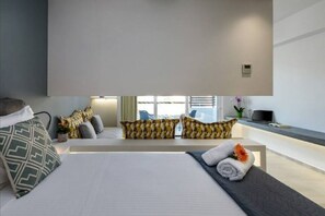 Relax in a stylish space with a large bed, sofa, and potted plant.