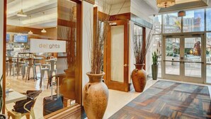 A hotel lobby with a reception desk, large vases, and a view of the outdoor seating area.